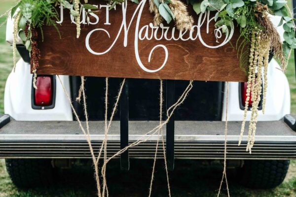 A Wedding Signboard just married, on a golf carriage adorned with flowers and tin cans on the golf course. Wedding ceremony and transportation.